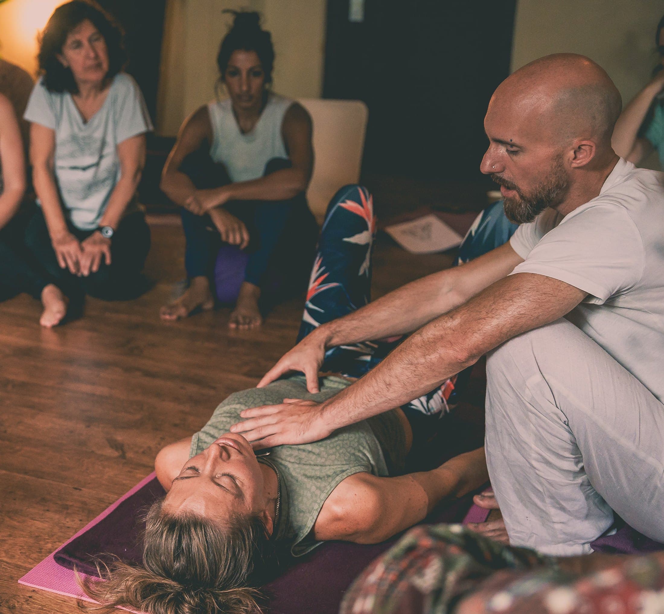 Ben North demonstrating a de-armouring technique on a client's chest, viewed from above as students look on.